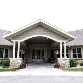 A residential building entrance with a covered porch and landscaping.