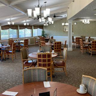 A spacious dining area featuring neatly arranged tables and chairs, illuminated by modern lighting fixtures.
