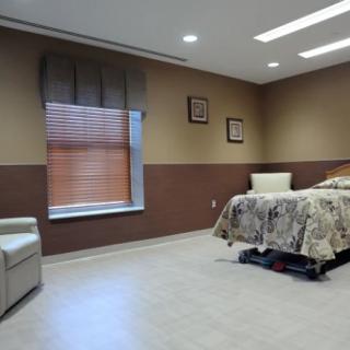 A cozy hospital room with a bed, armchair, and window.