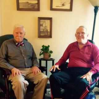 Two elderly men seated in a cozy living room setting.