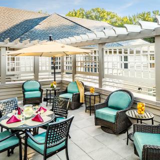 A cozy outdoor patio area with comfortable seating and a large umbrella, perfect for relaxation under the sun.