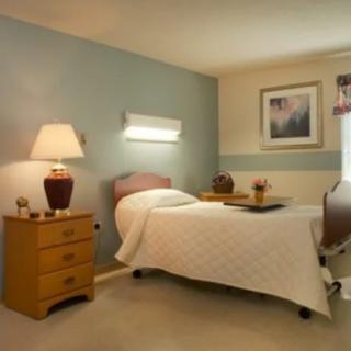 A cozy bedroom with a single bed and a nightstand featuring a lamp.