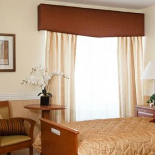 A cozy bedroom with a neatly made bed, soft lighting, and elegant curtains.