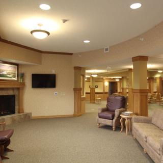 A cozy lobby interior featuring a fireplace, seating area, and television.