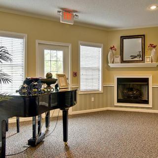 A cozy living room featuring a grand piano and a fireplace.