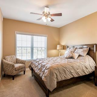 A cozy and inviting bedroom featuring a queen-sized bed, a comfortable chair, and plenty of natural light.