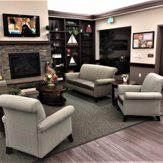 A cozy living room with sofas and a fireplace, featuring a television and bookshelves.
