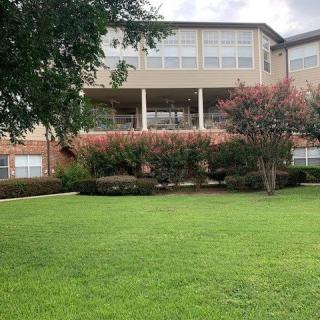 A residential building with a well-maintained lawn and surrounding trees.