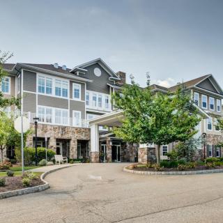 Front view of a residential building with trees and landscaped entrance.