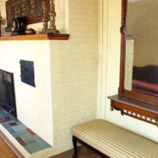 A cozy interior with a fireplace, large mirror, and cushioned bench.