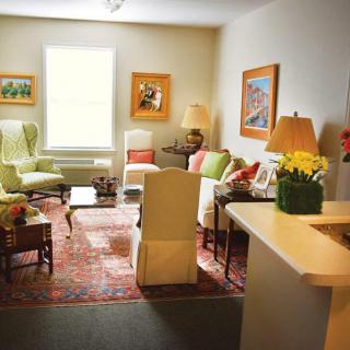 A cozy living room with a blend of colorful furniture and artwork, illuminated by natural light.