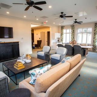A modern living room with comfortable seating, a flat-screen TV, and large windows providing natural light.