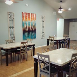 A modern dining area featuring several tables and chairs, complemented by eye-catching artwork on the wall.