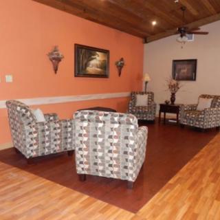 A cozy living room with patterned armchairs, warm wooden flooring, and decorative wall art.