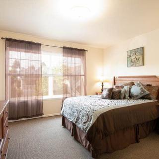 A cozy bedroom with a large bed, soft lighting, and sheer curtains.