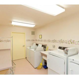 A well-lit laundry room featuring multiple washing machines and a dryer.
