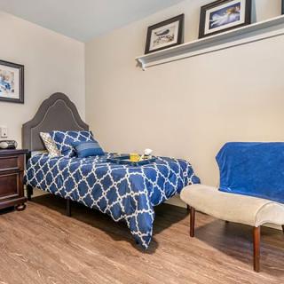 A cozy bedroom with a single bed, blue patterned bedding, and simple home decor.