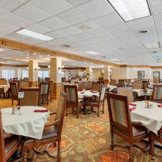A spacious restaurant dining area featuring neatly arranged tables and chairs, with overhead ceiling lights illuminating the space.