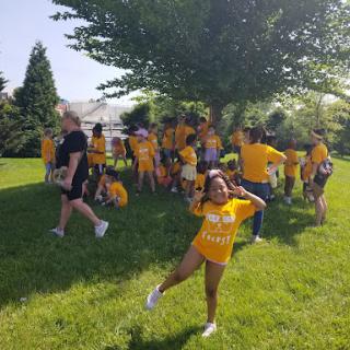 A lively group of children enjoying a sunny day outdoors, all wearing matching yellow shirts.