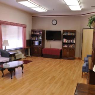 A cozy living room with a television, bookshelves, and comfortable seating.