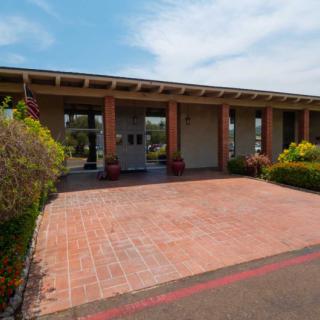 A modern building entrance with a brick driveway and landscaped surroundings.