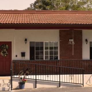 A small building entrance with a ramp, featuring a red door and roof.