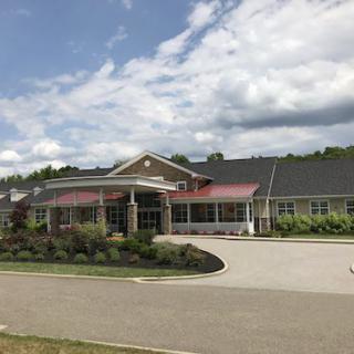 A view of a single-story building with a landscaped entrance and a cloudy sky.