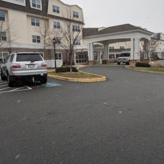 A view of a hotel entrance with an SUV parked in the lot on a cloudy day.