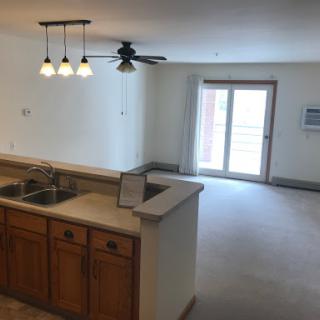 A spacious open-concept living area featuring a kitchen with wooden cabinets and a sliding glass door leading to the outdoors.