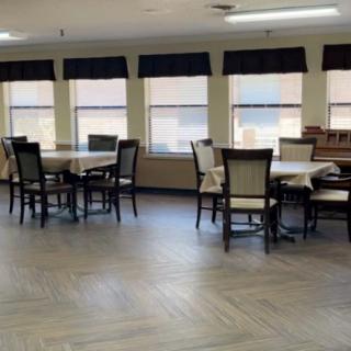 An empty dining area with several tables and chairs arranged near large windows.