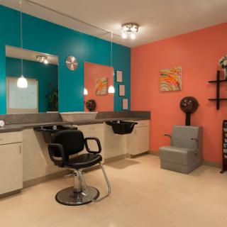 A vibrant hair salon featuring a mix of teal and coral walls, equipped with modern furniture and styling stations.