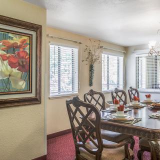 A well-decorated dining room featuring a wooden dining table with chairs, a chandelier, and a colorful painting on the wall.