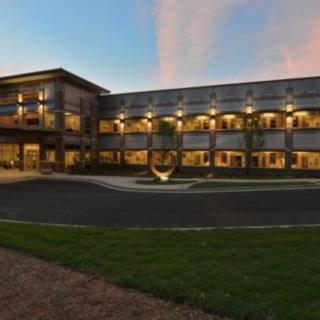 A well-lit modern hotel building during the evening, showcasing its architecture and landscaped surroundings.