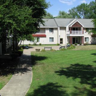 A serene residential building surrounded by a well-maintained garden and walkway.