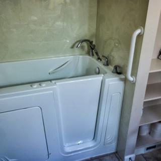A modern walk-in bathtub equipped with safety handles for accessibility.
