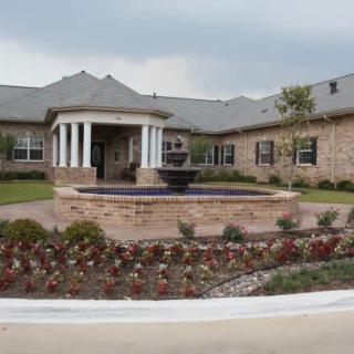 A well-maintained building exterior with a central fountain and landscaped garden.