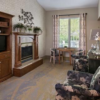 A cozy living room featuring a fireplace, television, and floral-patterned chairs.