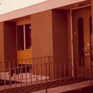 Exterior view of a building with a door, window, and railing.