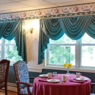 A cozy dining area with a round table set for four, adorned with elegant curtains and comfortable chairs.