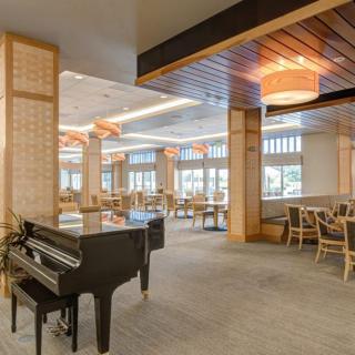 A modern restaurant interior featuring a grand piano and elegant seating areas.