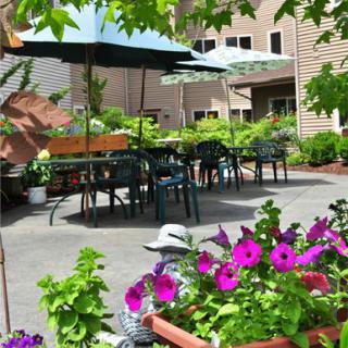 A charming outdoor patio with tables and chairs surrounded by vibrant flowers.