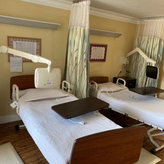 A hospital room with two empty patient beds separated by curtains.