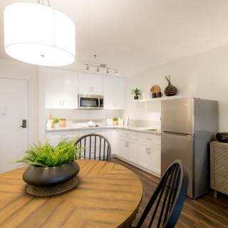 A modern kitchen with a dining area featuring a round wooden table and contemporary lighting.