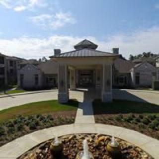 A building with a covered entrance and landscaped surroundings.