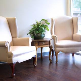 A cozy seating area featuring two elegant chairs and a lush plant.