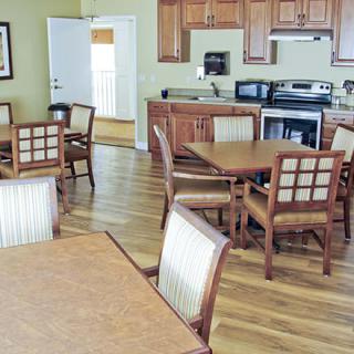 A cozy kitchen and dining area featuring wooden tables, chairs, and cabinets.