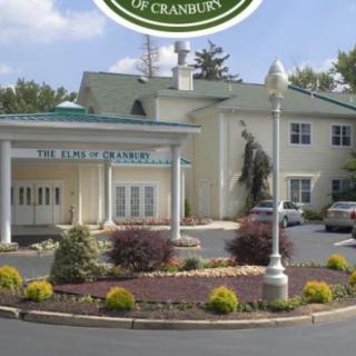 The entrance of a hotel with a landscaped area and parking space.