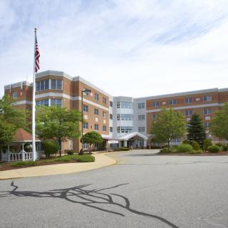 Exterior view of a hospital building with an American flag and surrounding greenery.