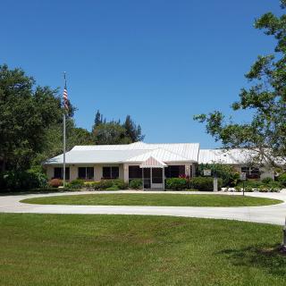 A suburban house with a circular driveway and a well-maintained lawn.