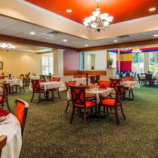 An elegant restaurant dining area with red-accented chairs and chandeliers.